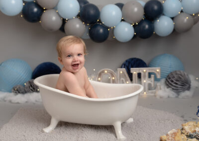baby boy having a splash in the bath during a cake smash